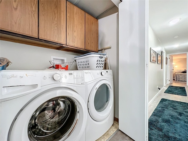 clothes washing area with light tile patterned floors, cabinets, and washing machine and clothes dryer