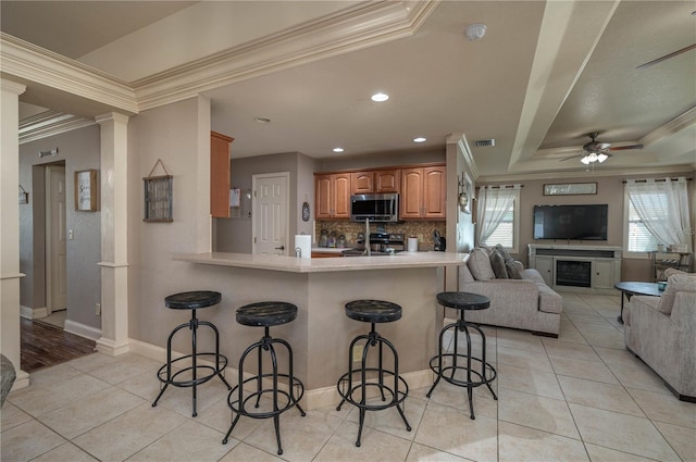 kitchen with a breakfast bar area, stainless steel appliances, kitchen peninsula, and a healthy amount of sunlight