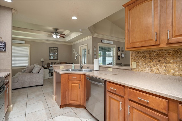 kitchen with sink, a tray ceiling, ornamental molding, stainless steel dishwasher, and kitchen peninsula