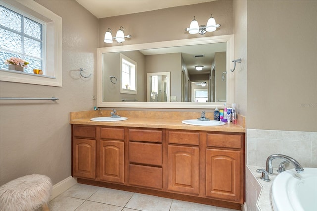 bathroom with tiled tub, vanity, and tile patterned floors