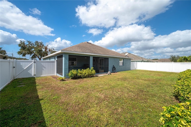 rear view of house with a yard and a sunroom