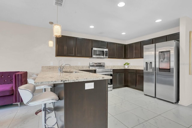 kitchen featuring a kitchen breakfast bar, hanging light fixtures, kitchen peninsula, sink, and appliances with stainless steel finishes