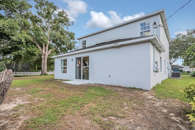 back of property with central AC and a lawn