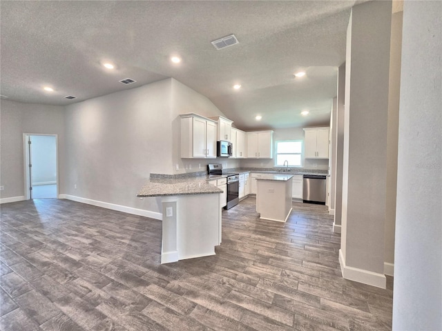 kitchen featuring a textured ceiling, visible vents, stainless steel appliances, and dark wood finished floors