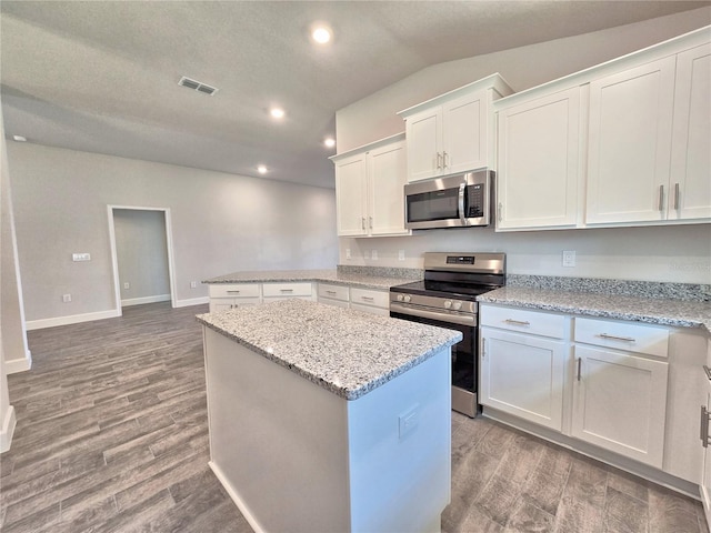 kitchen with appliances with stainless steel finishes, a center island, light wood-type flooring, visible vents, and white cabinets