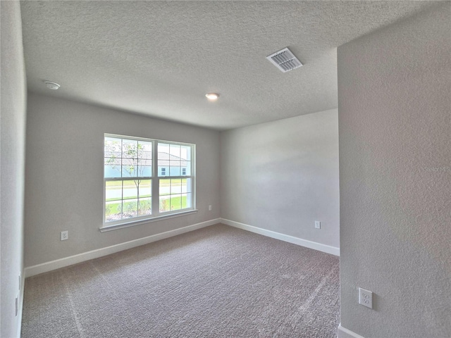 empty room with carpet, baseboards, a textured ceiling, and visible vents