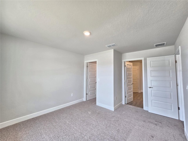 unfurnished bedroom with baseboards, carpet floors, a textured ceiling, and visible vents