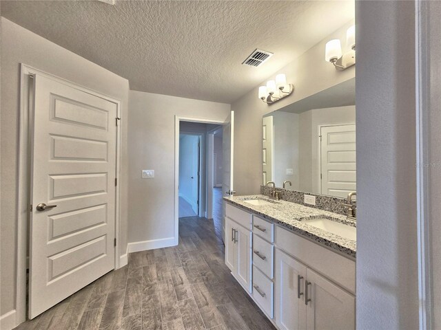 bathroom with wood finished floors, a sink, double vanity, and visible vents