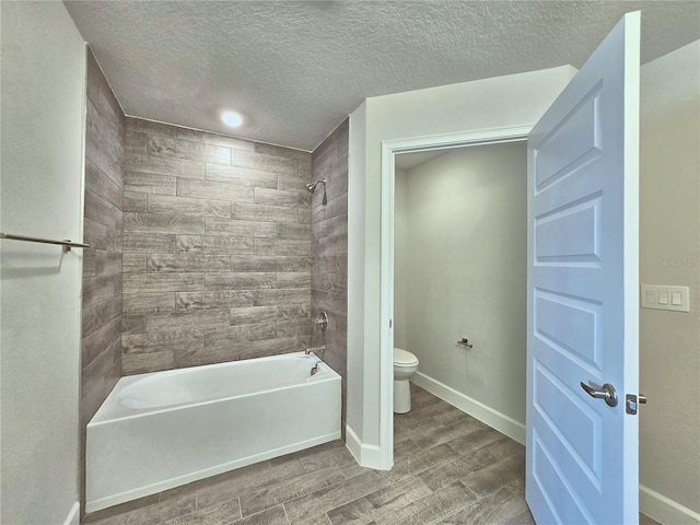 full bathroom featuring toilet, baseboards, a textured ceiling,  shower combination, and wood finished floors