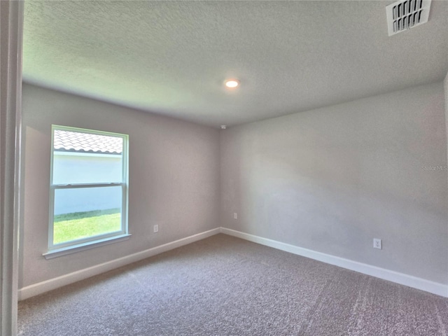 carpeted spare room with baseboards, a textured ceiling, and visible vents