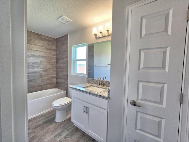 bathroom featuring toilet, vanity, wood finished floors, a textured ceiling, and visible vents