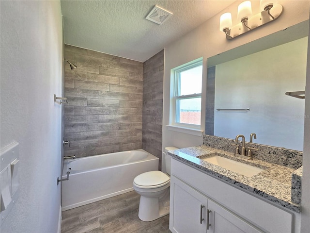 full bath featuring toilet, vanity, wood finished floors, a textured ceiling, and visible vents