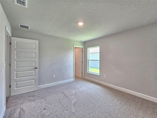 unfurnished bedroom with baseboards, visible vents, carpet flooring, and a textured ceiling