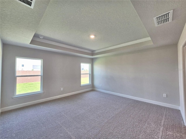 carpeted empty room with baseboards, visible vents, and a raised ceiling