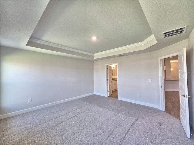 unfurnished bedroom with a textured ceiling, carpet flooring, a tray ceiling, and visible vents