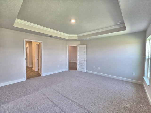 unfurnished bedroom with a textured ceiling, a tray ceiling, visible vents, and crown molding