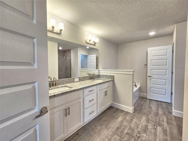 bathroom with a stall shower, wood finished floors, a sink, and a garden tub