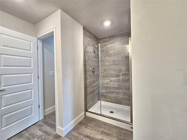 full bathroom with wood finish floors, a stall shower, baseboards, and a textured ceiling