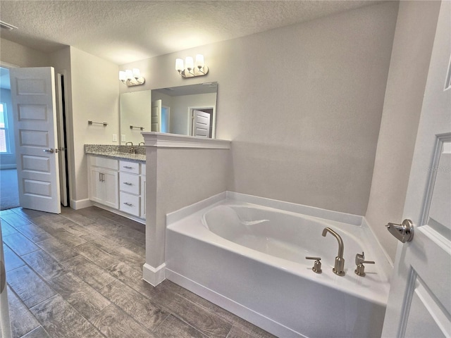 full bath featuring a textured ceiling, wood tiled floor, a garden tub, and vanity