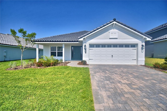 single story home with a tile roof, stucco siding, an attached garage, a front lawn, and decorative driveway
