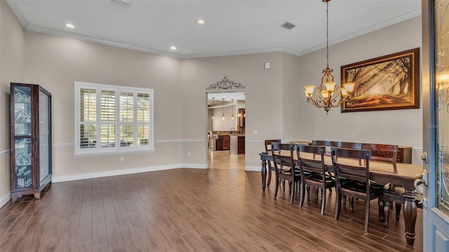 dining space featuring crown molding, hardwood / wood-style flooring, and a chandelier