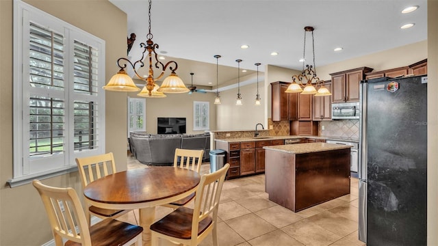 kitchen featuring appliances with stainless steel finishes, sink, kitchen peninsula, pendant lighting, and light tile patterned floors