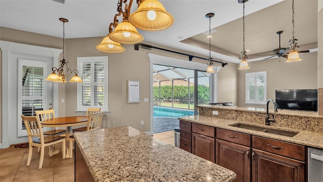 kitchen with a healthy amount of sunlight, light stone countertops, sink, and light tile patterned flooring