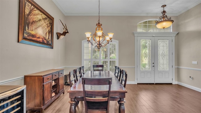 dining room featuring french doors, hardwood / wood-style floors, crown molding, an inviting chandelier, and beverage cooler