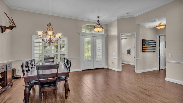 dining room featuring an inviting chandelier, crown molding, french doors, and hardwood / wood-style flooring