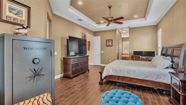 bedroom with ornamental molding, wood-type flooring, a tray ceiling, and ceiling fan