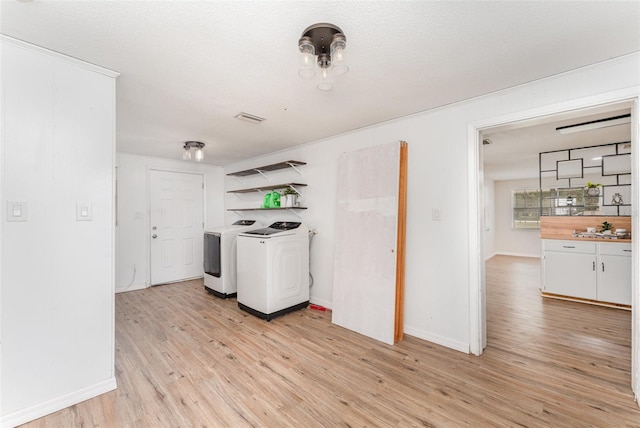 laundry room with light hardwood / wood-style floors, washing machine and dryer, and a textured ceiling