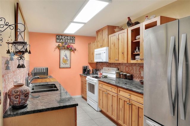 kitchen featuring decorative backsplash, white appliances, sink, light tile patterned floors, and dark stone countertops