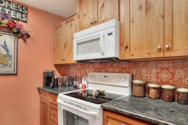 kitchen with white appliances, backsplash, and dark stone counters