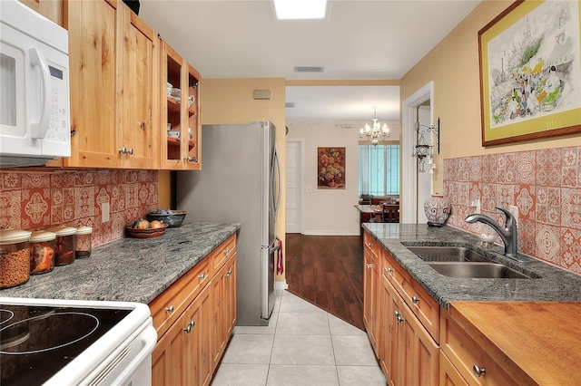 kitchen featuring decorative backsplash, dark stone counters, sink, an inviting chandelier, and light tile patterned flooring