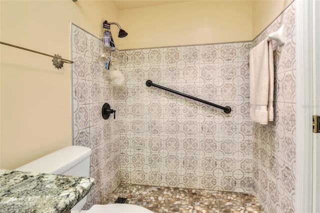 bathroom with a tile shower and toilet