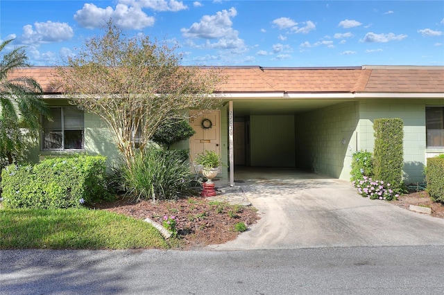 view of front of property with a shingled roof, concrete driveway, and a carport