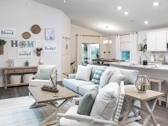 living room featuring lofted ceiling, a chandelier, wood-type flooring, and sink