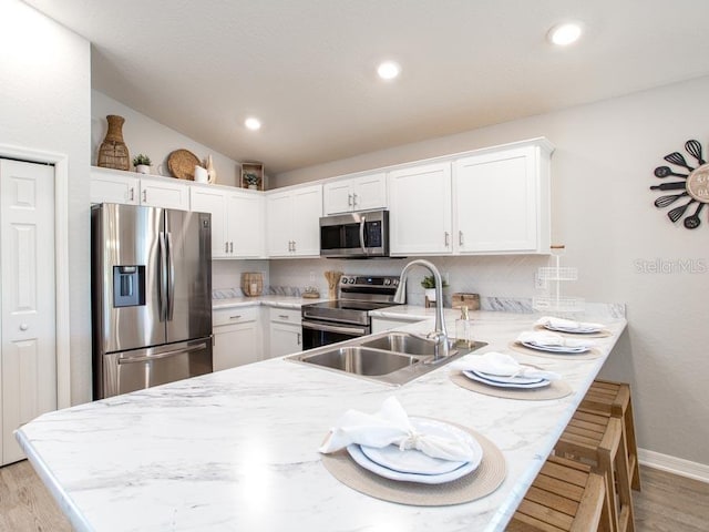 kitchen featuring appliances with stainless steel finishes, sink, kitchen peninsula, vaulted ceiling, and white cabinets