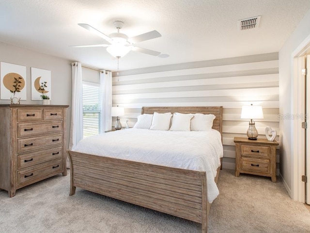 bedroom featuring ceiling fan, light carpet, and a textured ceiling