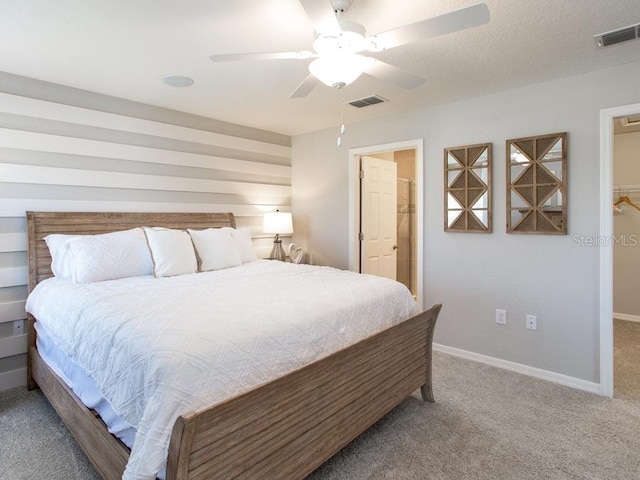 bedroom with a spacious closet, carpet, and ceiling fan