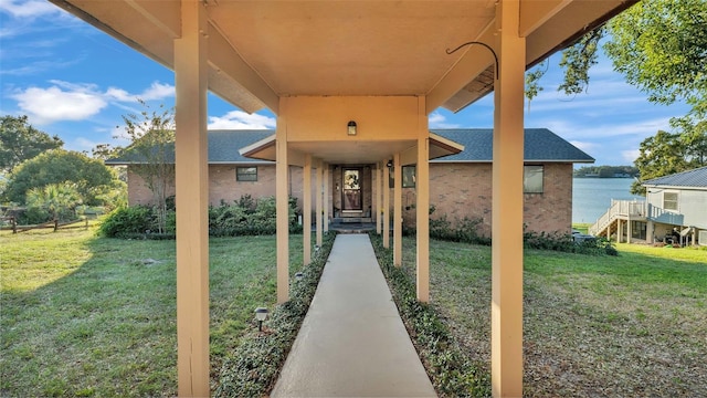 entrance to property featuring a lawn and a water view