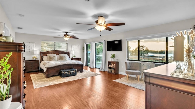 bedroom with ceiling fan, access to exterior, light hardwood / wood-style floors, and multiple windows