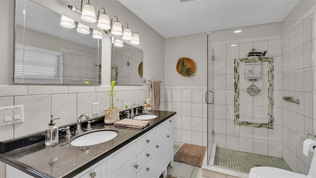 bathroom with tile patterned flooring, a shower with door, vanity, tile walls, and toilet