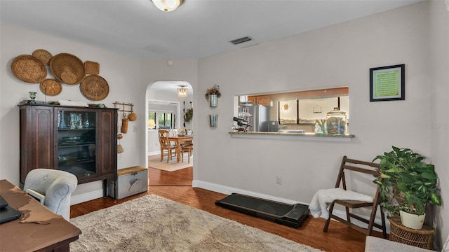 office featuring baseboards, visible vents, arched walkways, and wood finished floors