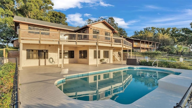 rear view of property with fence, stairs, stucco siding, an outdoor pool, and a patio area