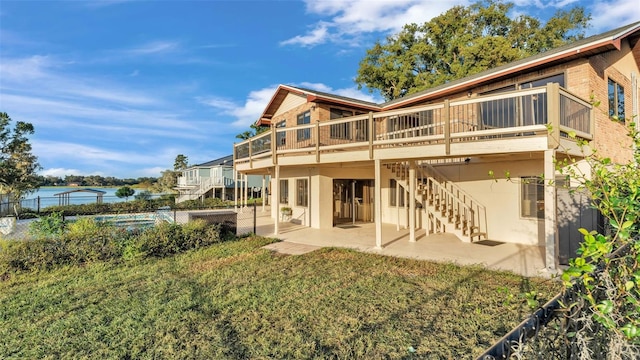 rear view of property with a patio, a deck with water view, fence, stairs, and a lawn