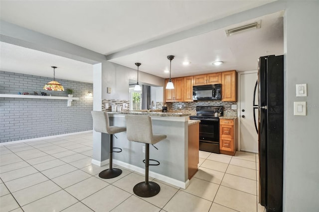 kitchen with a kitchen bar, light tile patterned floors, black appliances, decorative light fixtures, and kitchen peninsula