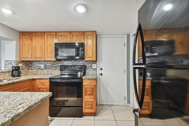 kitchen with light stone countertops, light tile patterned floors, backsplash, and black appliances