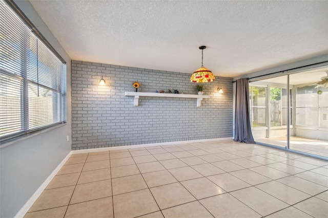 unfurnished dining area with light tile patterned floors, a healthy amount of sunlight, and brick wall