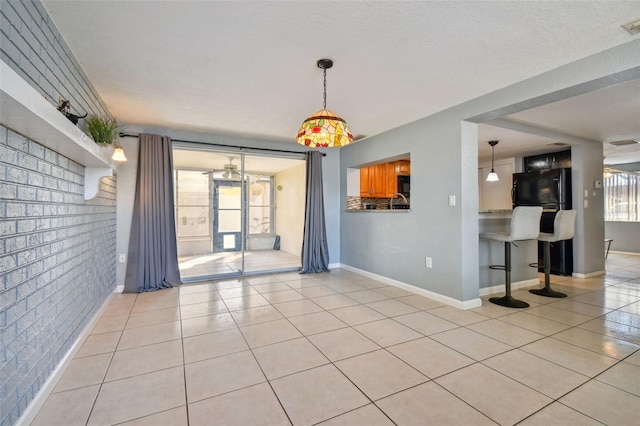 unfurnished living room featuring brick wall, light tile patterned floors, and plenty of natural light